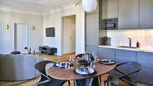 Een moderne keuken met grijze kastjes, een inbouwoven en een wit aanrecht.