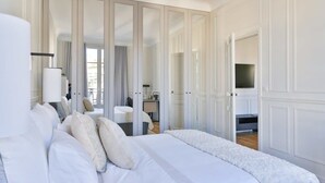 Een moderne hotelkamer met een groot bed, een televisie en een inloopkast met spiegeldeuren.