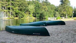 Una playa arenosa con tres kayaks verdes, etiquetados 'SAVANNAH' y 'KINO', junto al agua.