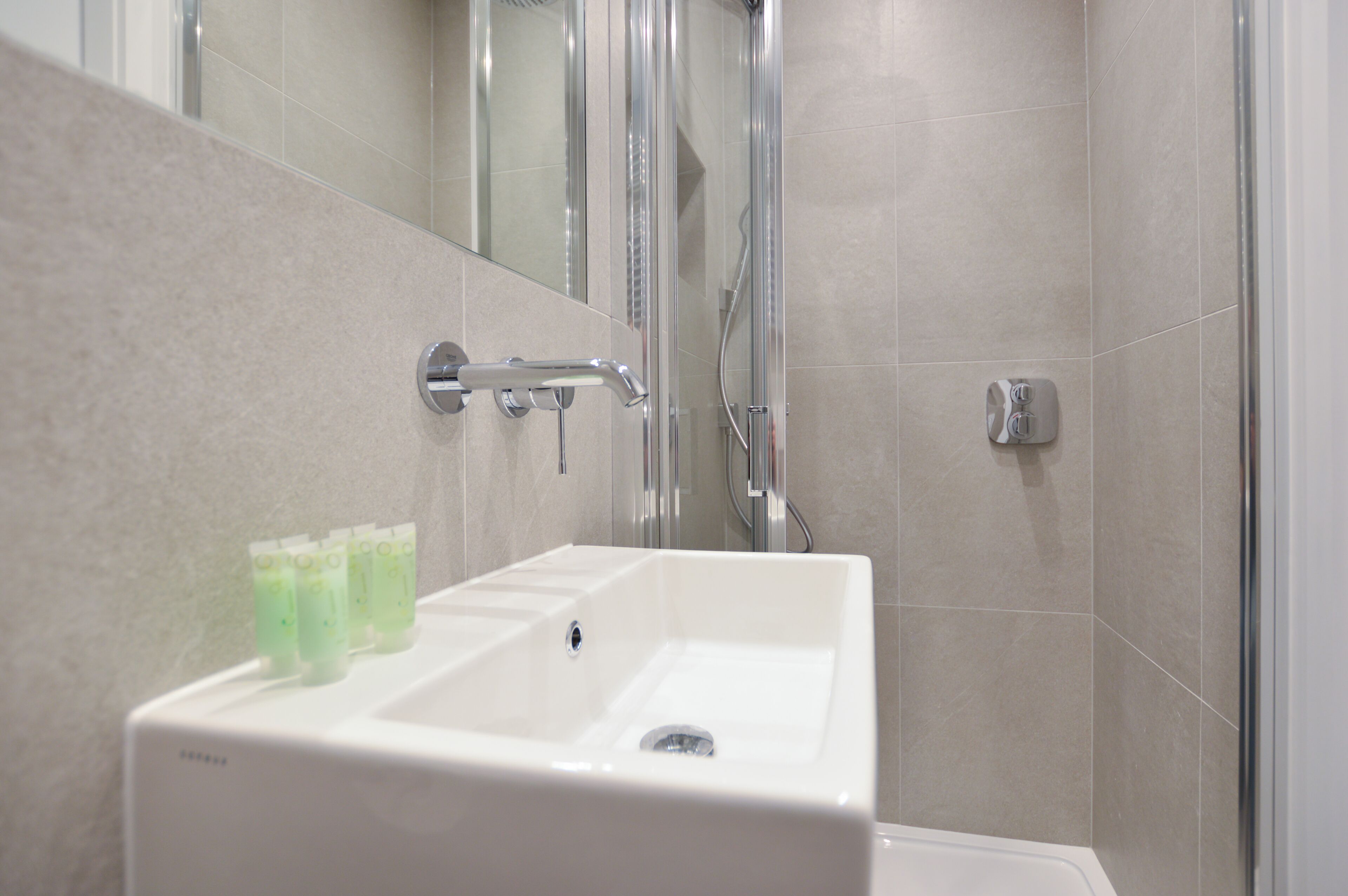 A modern bathroom with a white sink, a glass shower enclosure, and a mirror.