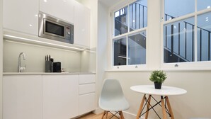 A modern kitchen with white cabinets, a stainless steel microwave, and a small table with a potted plant. -  StayPrime Marylebone Serviced Apartments (London)