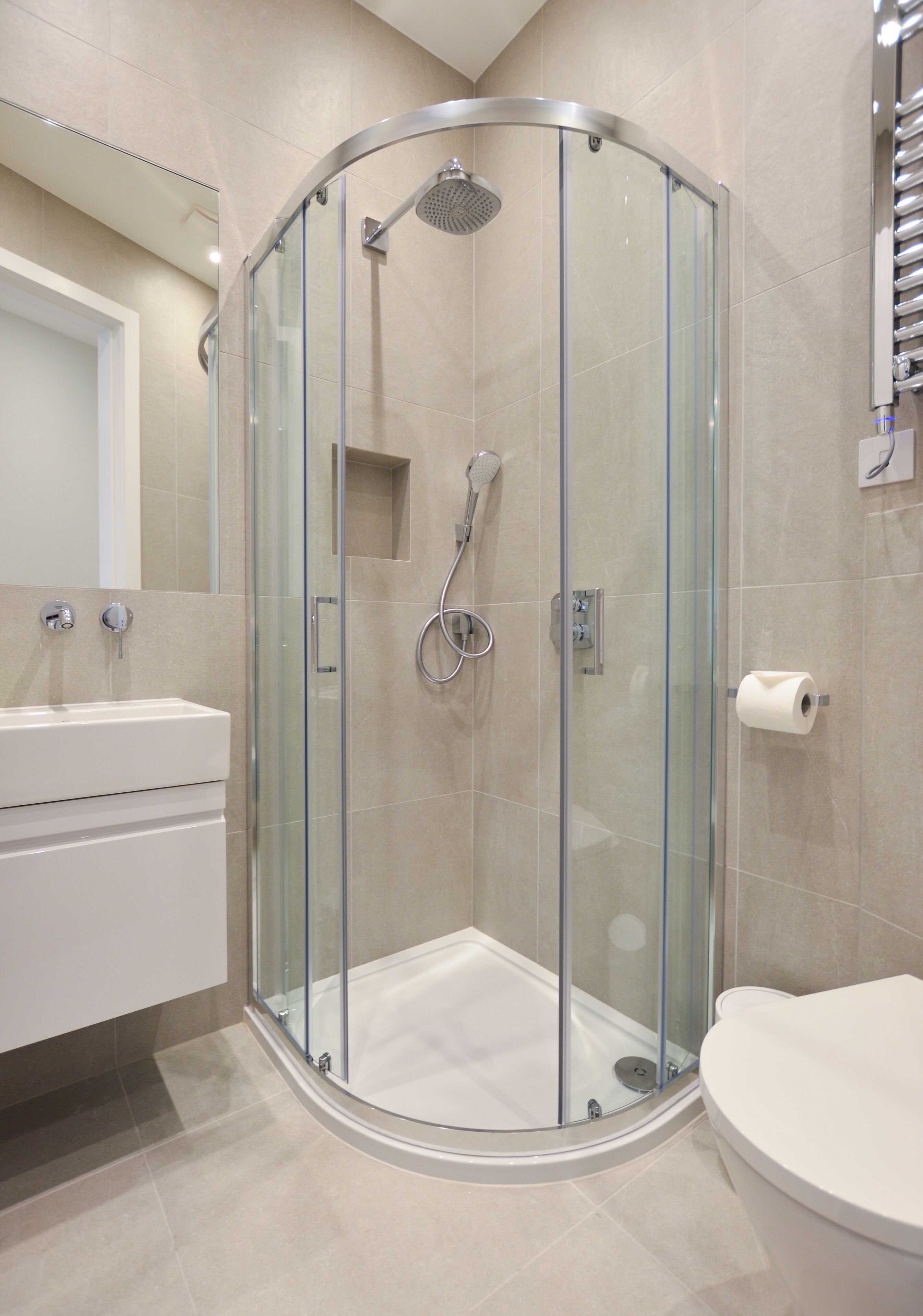 A modern bathroom with a glass-enclosed shower, a toilet, and a sink.
