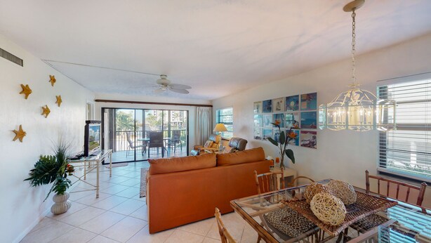 A spacious living area with a sofa, dining table, and chairs, a ceiling fan, and a balcony with a view. - Prime Location I Free Beach Access Directly Across The Street!!! (Marco Island)