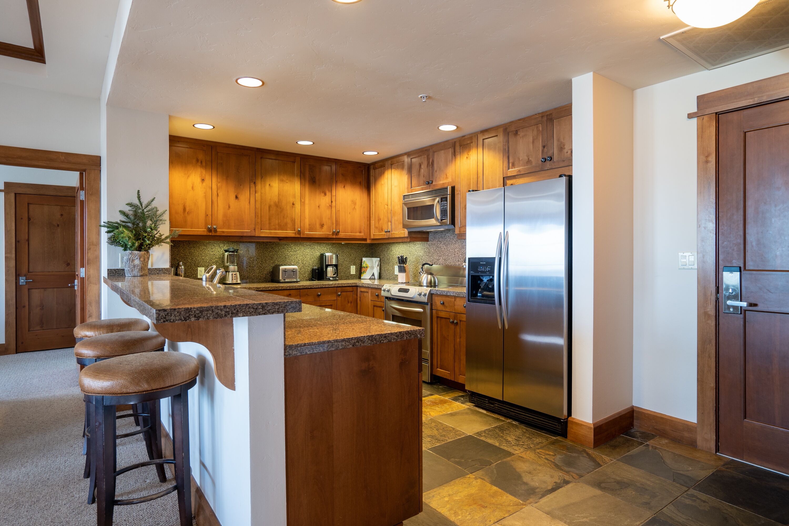 A modern kitchen with wooden cabinets, stainless steel appliances, and a granite countertop.