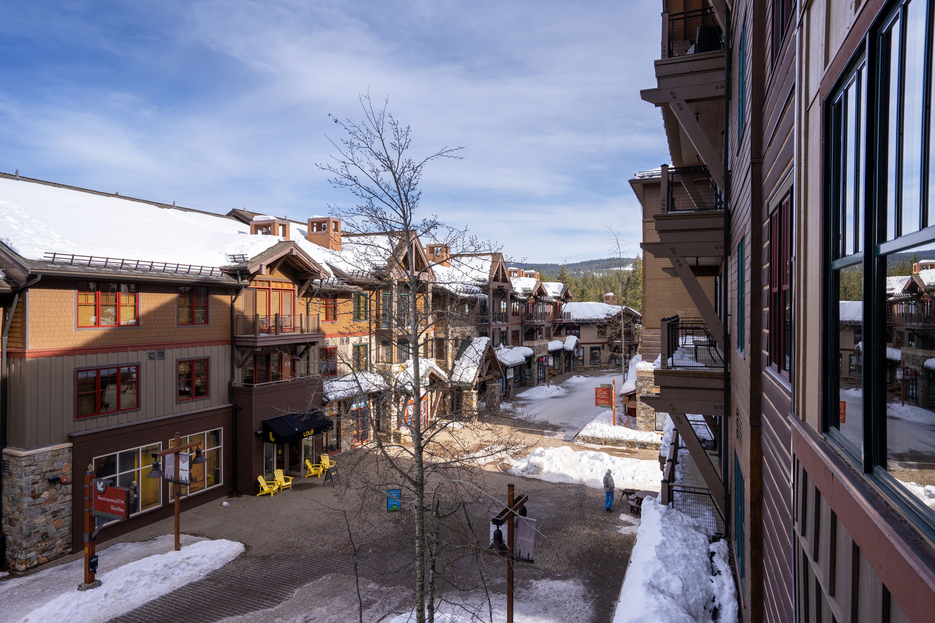 A snow-covered street with buildings, including a hotel with a balcony and a sign for a restaurant.