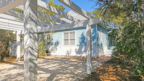A house with a porch, a small garden, and a wooden pergola.
