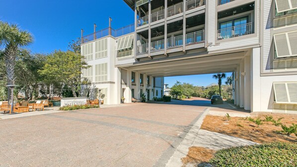 A multi-story hotel with a covered entrance, outdoor seating, and a clear sky.
