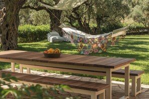 Una mesa de picnic con una cesta de fruta y una hamaca con una cubierta colorida de ganchillo.