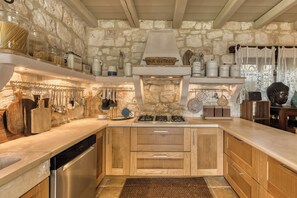 Una cocina rústica con paredes de piedra, armarios de madera y estufa empotrada.