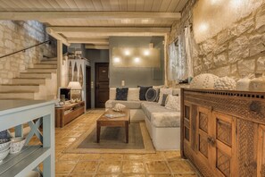Una sala de estar acogedora con pared de piedra, un aparador de madera, un sofá y una mesa de centro.