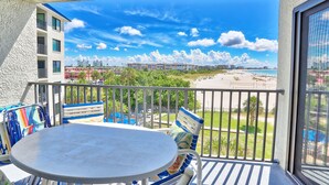 Ein Balkon mit Tisch und Stühlen mit Blick auf Strand und Stadt.