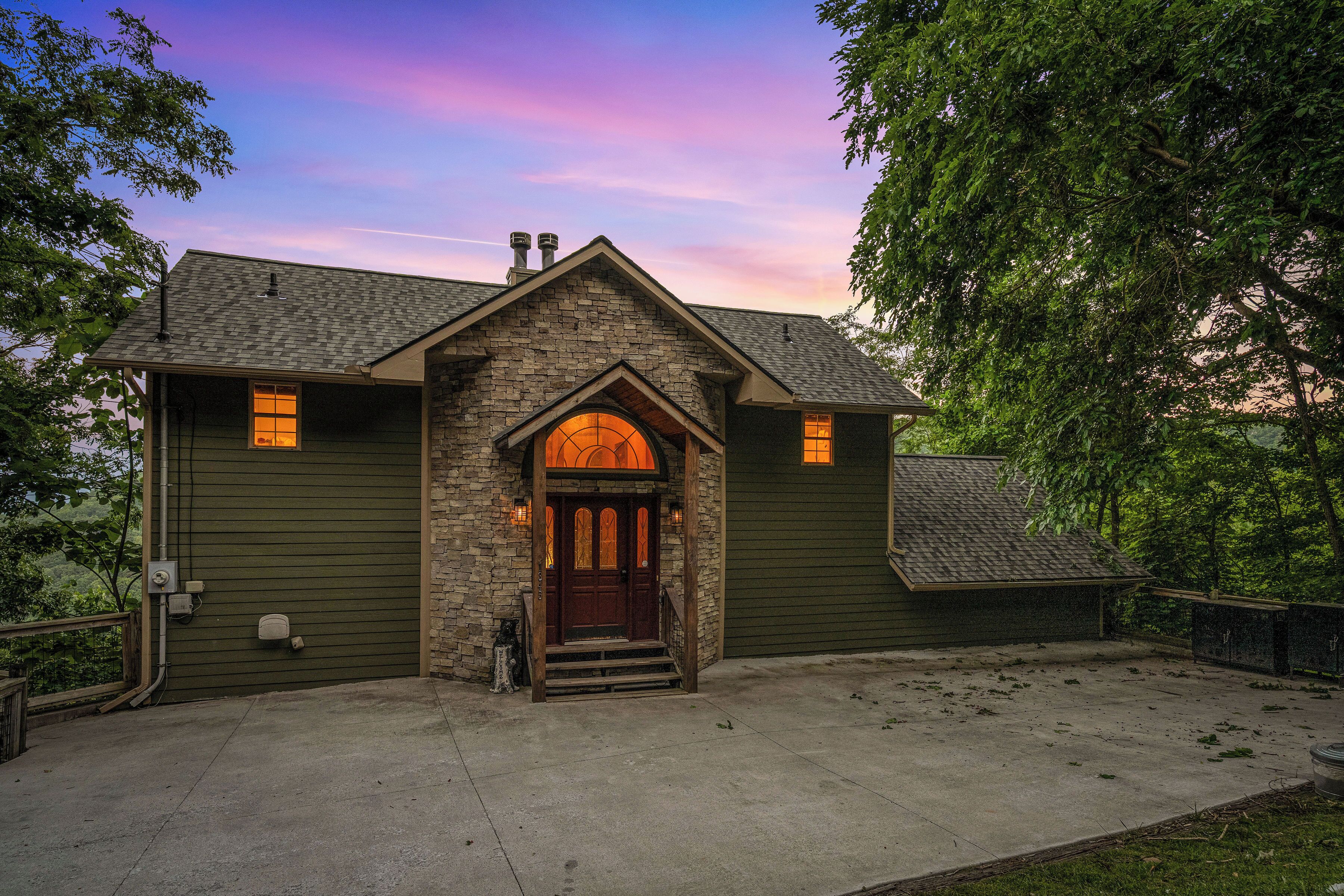 A two-story house with a stone facade, a wooden front door, and a small porch.