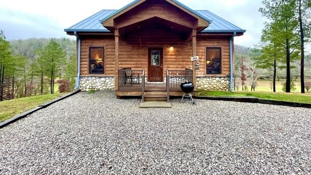 A log cabin with a porch, a grill, and a gravel driveway. - Charming, pet friendly cabin, perfect for fishing, family, hiking and R&R! 2 Bedroom Cabin by RedAwning (Tellico Plains)