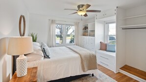 A bedroom with a bed, a bedside table with a lamp, a ceiling fan, a window with curtains, a built-in bench, and a wardrobe. - "sweet Serenity" Stay 10 Minutes From Hershey 3 Bedroom Home by RedAwning (Palmyra)