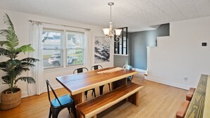 A dining area with a wooden table and benches, a chandelier, and a potted plant. - "sweet Serenity" Stay 10 Minutes From Hershey 3 Bedroom Home by RedAwning (Palmyra)