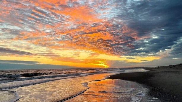 Una playa con atardecer y nubes.