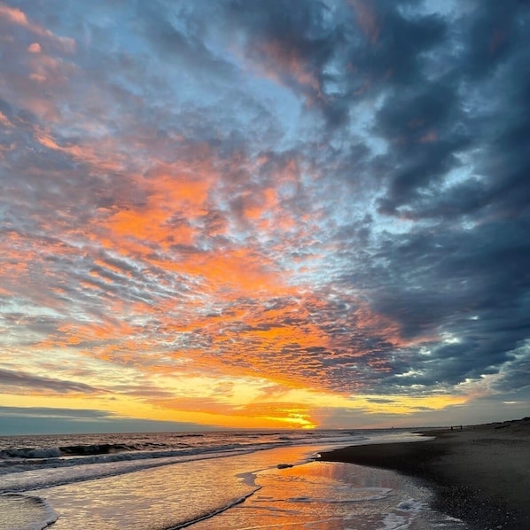 Une plage au coucher du soleil, avec des nuages.