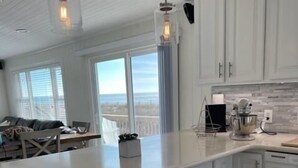 Una cocina moderna con armarios blancos, una isla grande y vista al océano.