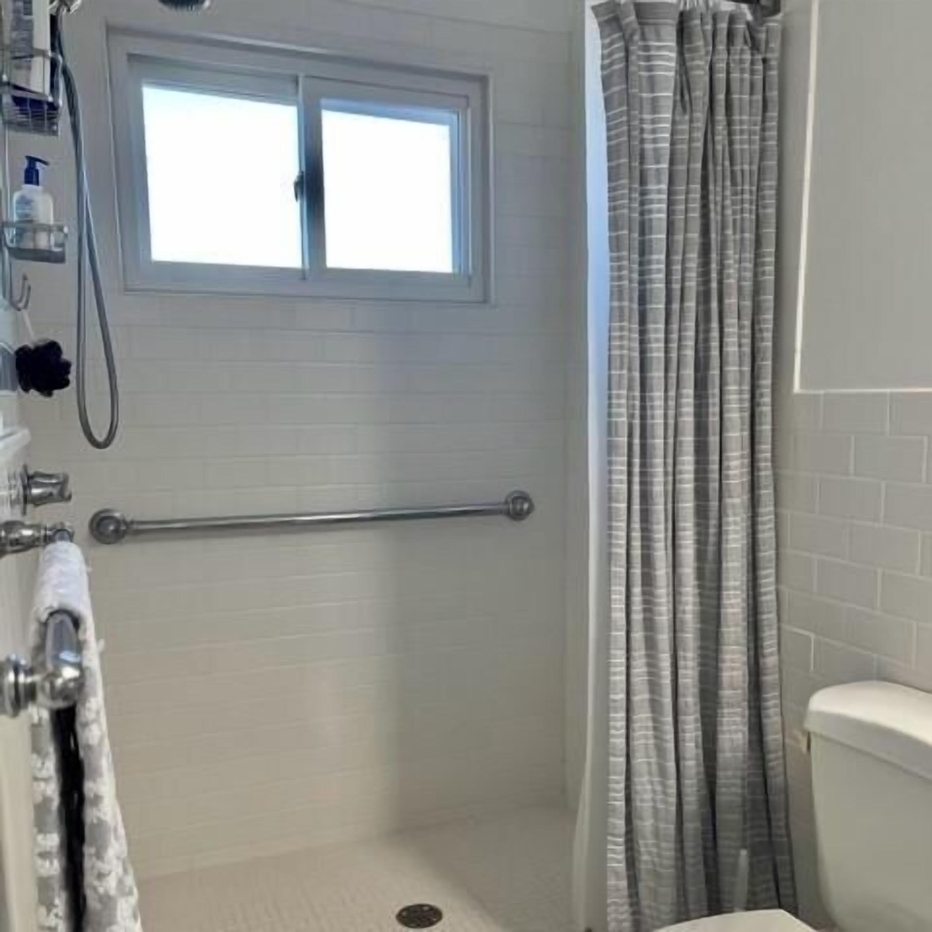 Un baño con ducha, ventana y retrete.