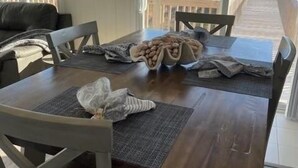 Un comedor con mesa de madera, sillas y vistas a la playa a través de amplios ventanales.