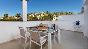 A terrace with a table set for two, a bottle of wine, and a small table with a potted plant. - RDR230 - Apt. Aloha Royal (Marbella)