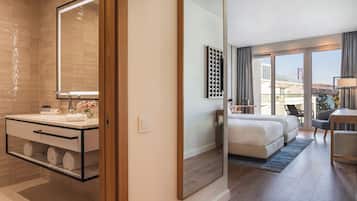 Habitación de hotel moderna con un espejo grande, un baño con tocador, una cama, un escritorio y vistas a un puente.