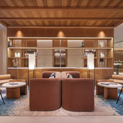A modern lobby with a central seating area, wooden paneling, and a glass partition.