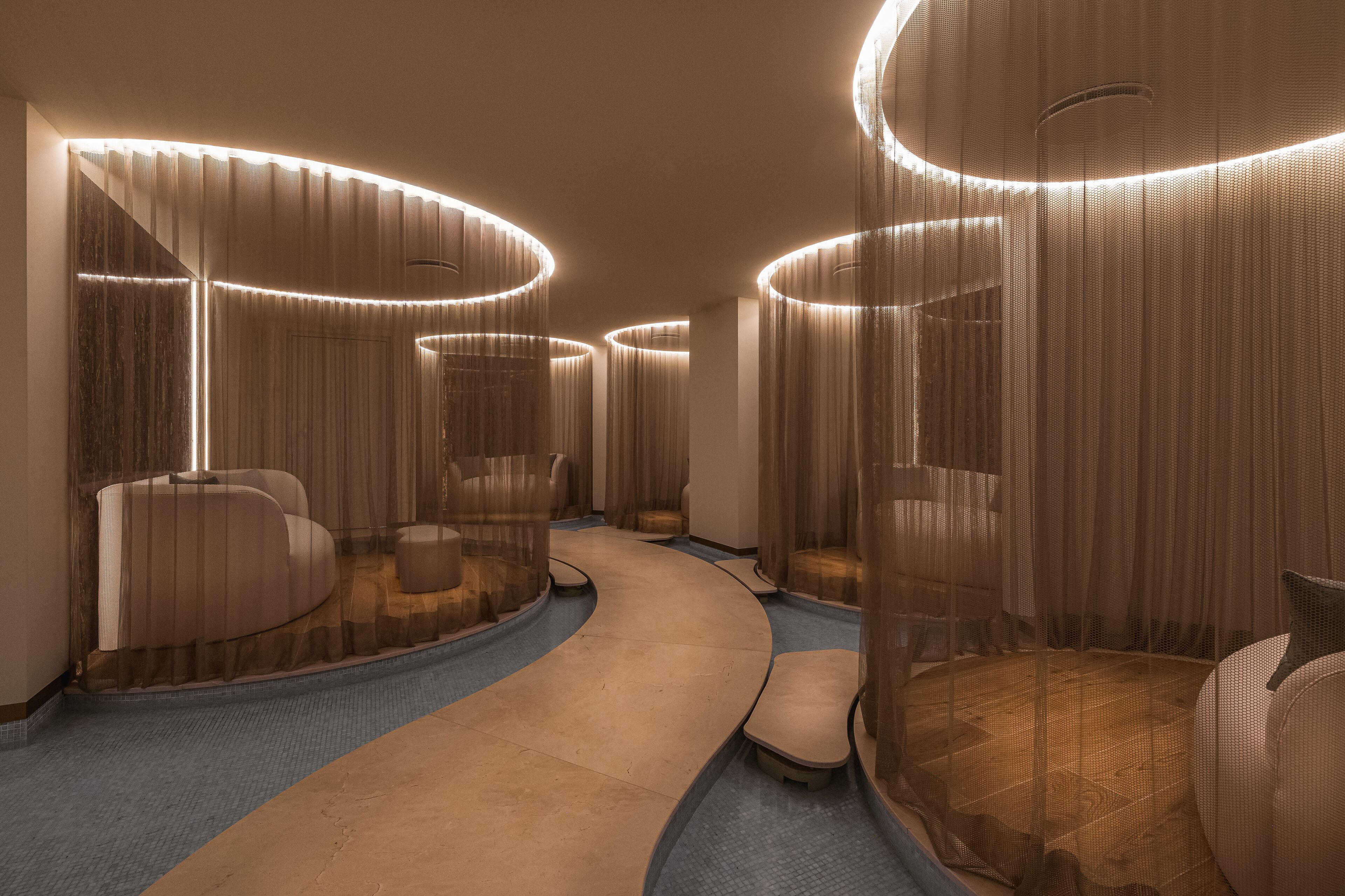 A modern hotel lobby with curved seating areas, a central walkway, and ambient lighting.