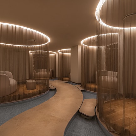 A modern hotel lobby with curved seating areas, a central walkway, and ambient lighting.