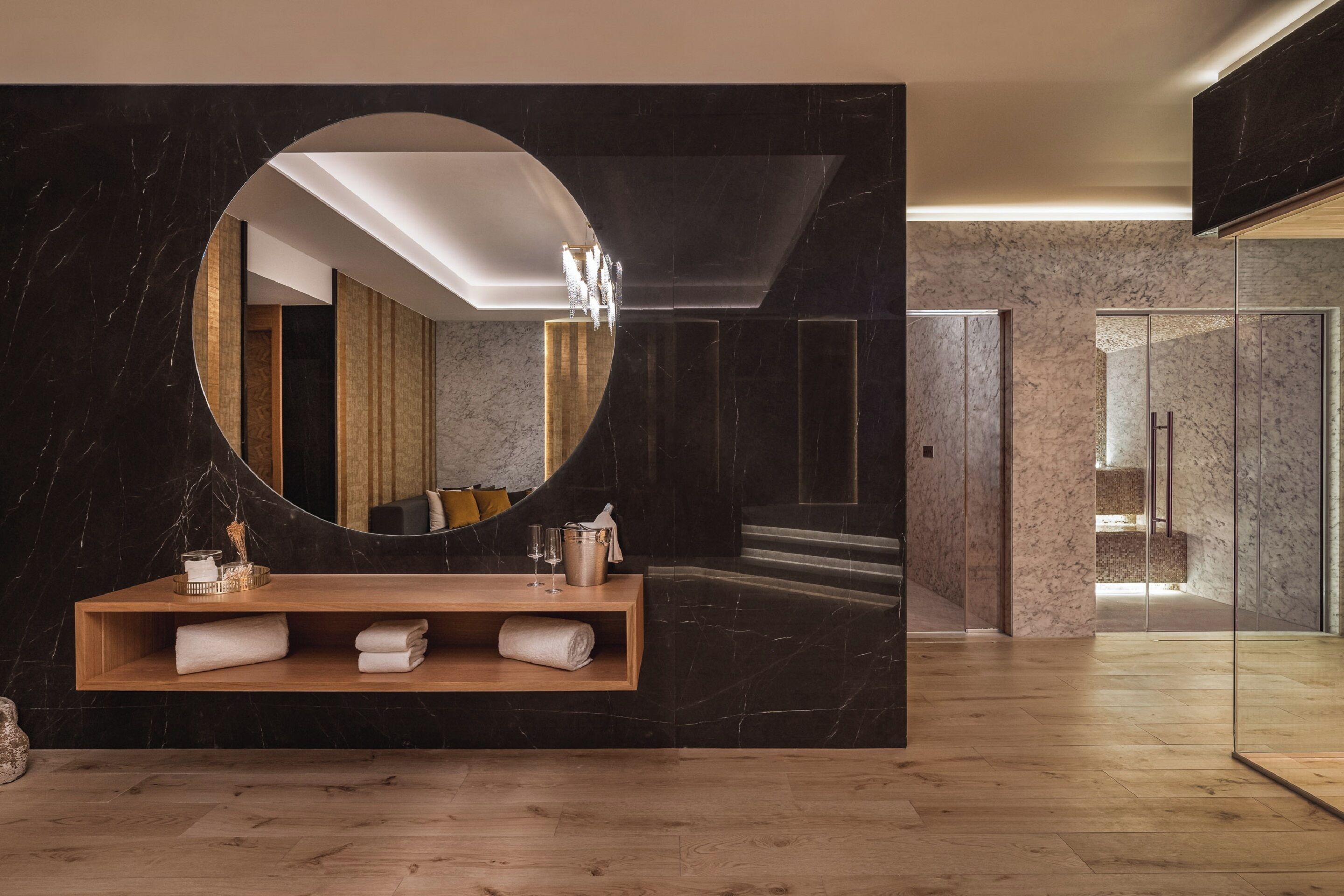 A modern bathroom with a large mirror, wooden vanity, and marble walls.