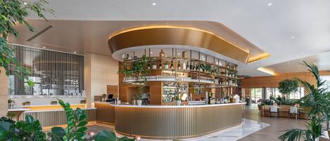 A modern bar area with a curved counter, shelves of bottles, and potted plants.