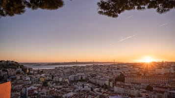 Une vue d’une ville au coucher du soleil, avec des bâtiments, un pont et une étendue d’eau.