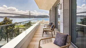 A balcony with wicker furniture and a view of a bridge over water. - Hyatt Regency Lisbon (Lisbon)