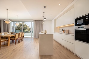 A modern kitchen with a central island, built-in appliances, and a dining area with natural light.