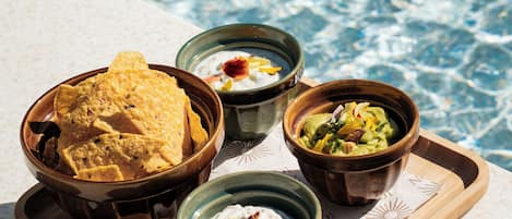 Una bandeja con fuentes de comida junto a una piscina.