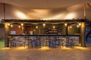 A bar area with a stone counter, bar stools, and a brick wall. - SALT of Akagera (Mwiri)
