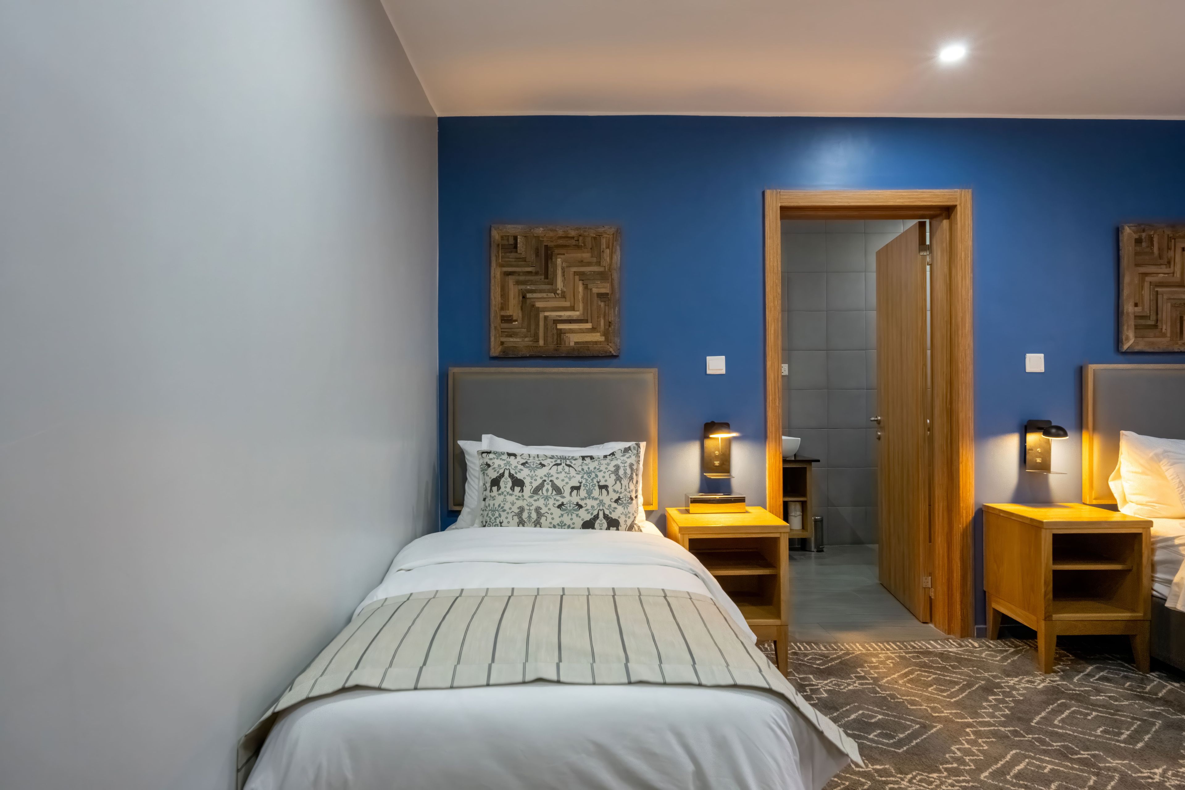 A bedroom with a bed, bedside tables, and a door leading to a bathroom.