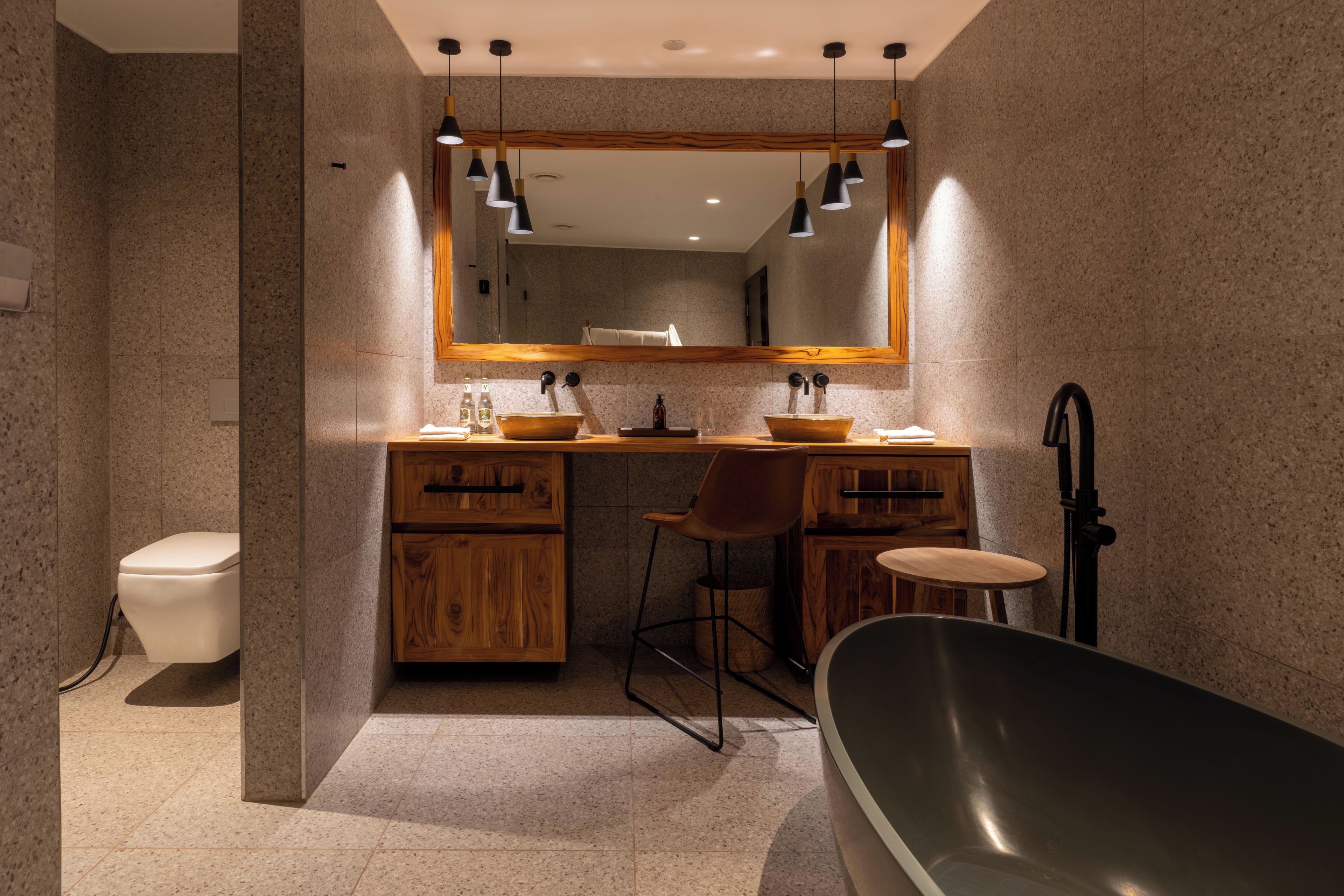 A modern bathroom with a freestanding bathtub, a wooden vanity with a mirror, and a toilet.