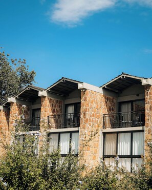 A row of stone buildings with balconies and large windows. - SALT of Akagera (Mwiri)