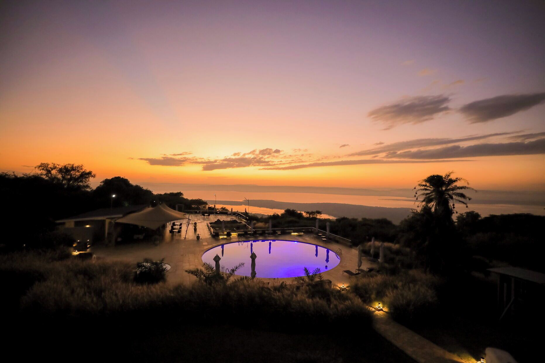 Una piscina con vista al atardecer y una masa de agua distante.