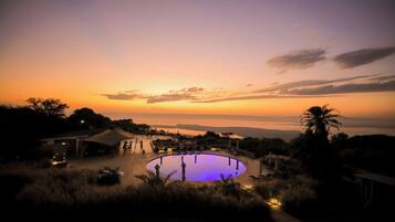 Una piscina con vista al atardecer y una masa de agua distante.