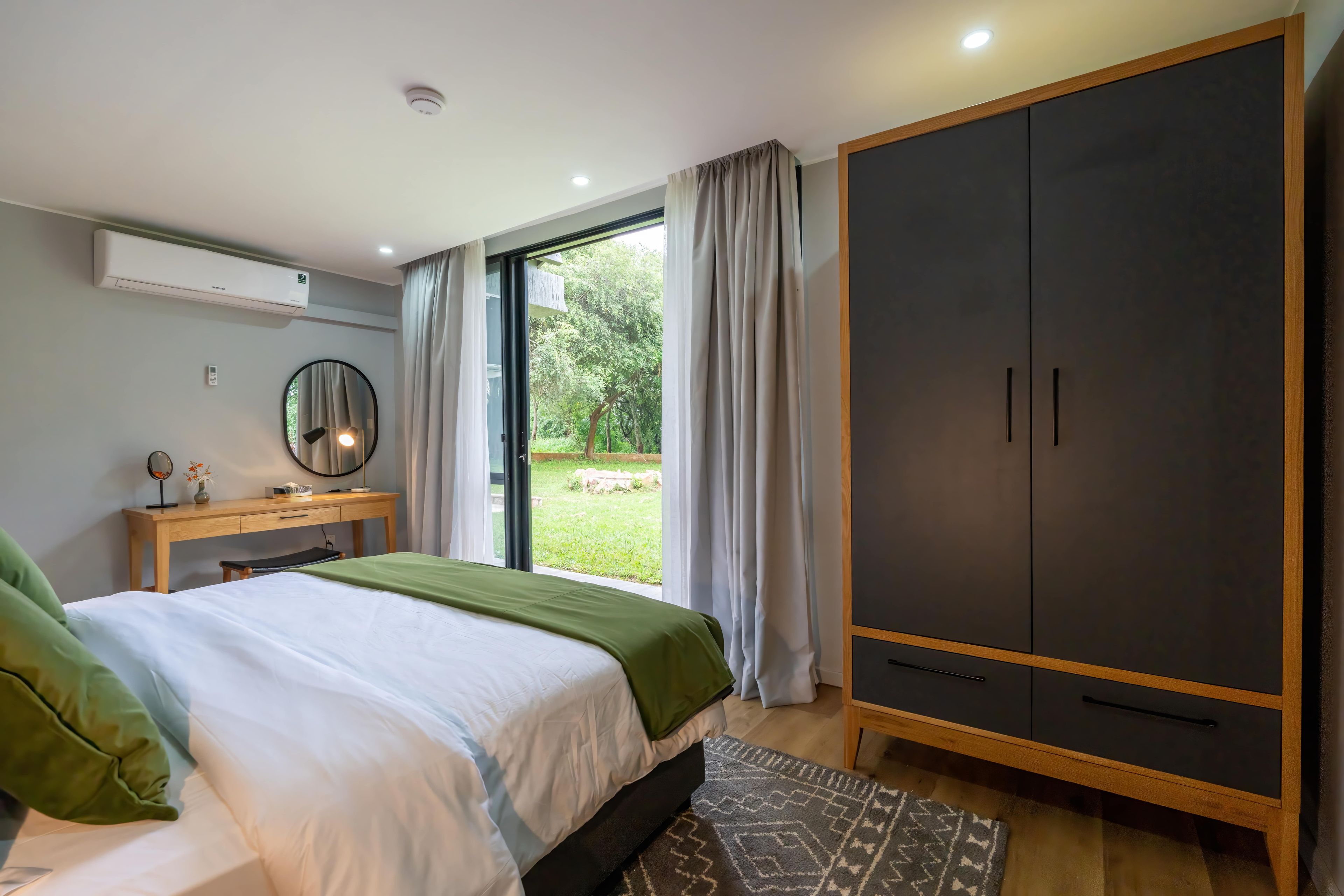 A bedroom with a bed, bedside table, mirror, and a wardrobe.