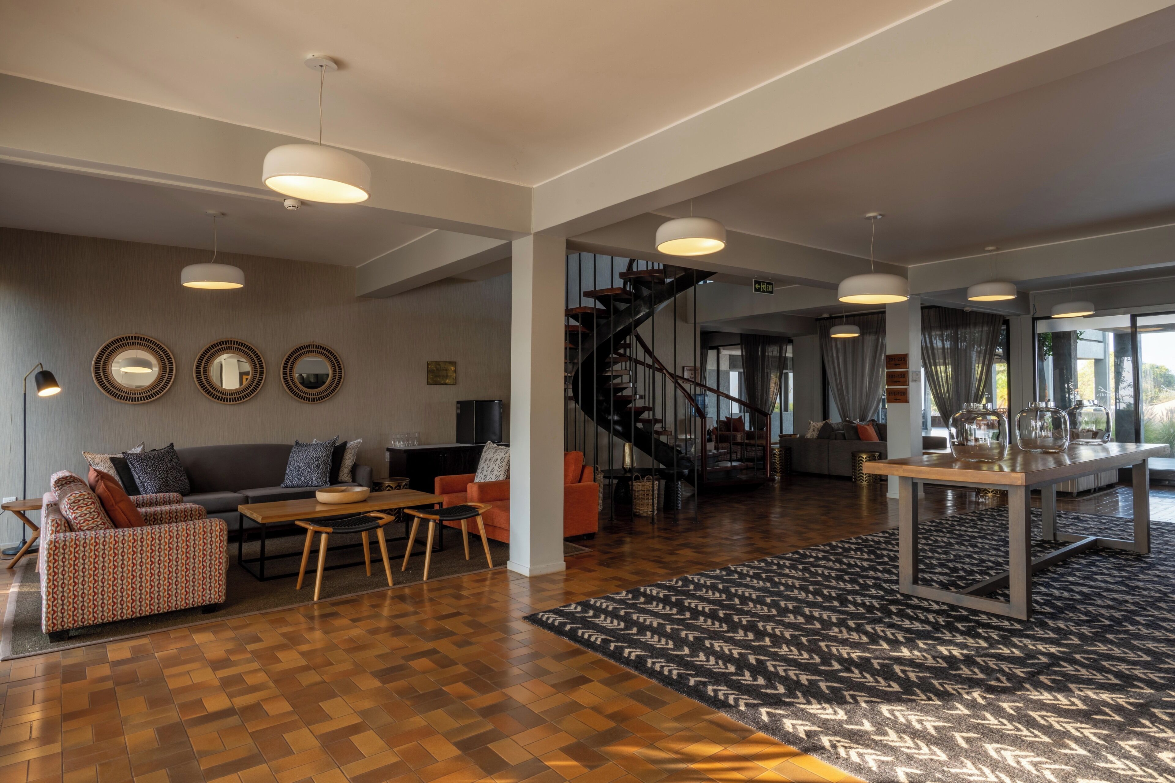 A spacious living area with a wooden floor, a sofa, a coffee table, and a staircase leading to an upper level.
