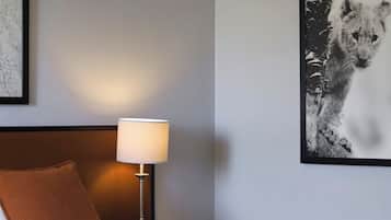 Una habitación de hotel con una cama, una mesita de noche con una lámpara, un cuadro enmarcado en la pared y una almohada.