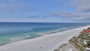 A beach with a clear view of the ocean, a sandy shore, and a building with a red roof. - 11th Floor 4 BR 3BA End unit in Tower 1 at the Majestic!! (Panama City Beach)