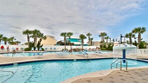 A swimming pool area with lounge chairs, palm trees, and a water fountain. - 11th Floor 4 BR 3BA End unit in Tower 1 at the Majestic!! (Panama City Beach)