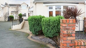 A residential street with houses, a paved driveway, and well-maintained hedges. - Bella Vita (Southport)