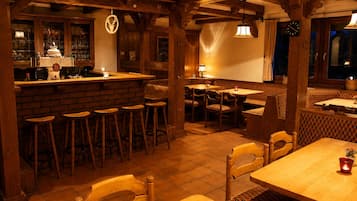 Un restaurant à l’ambiance chaleureuse, avec des poutres en bois, un bar et différents types de sièges.