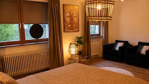 Ein Schlafzimmer mit einem großen Bett, einem Schlafsofa, einer Lampe und einem Fenster mit Vorhängen.