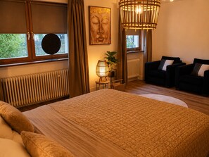 Una camera da letto con un letto grande, una poltrona, una lampada e una finestra con tende.